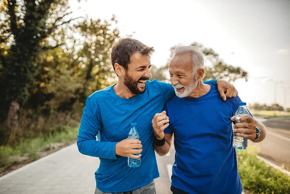 Two men laughing together on a walk with water bottles