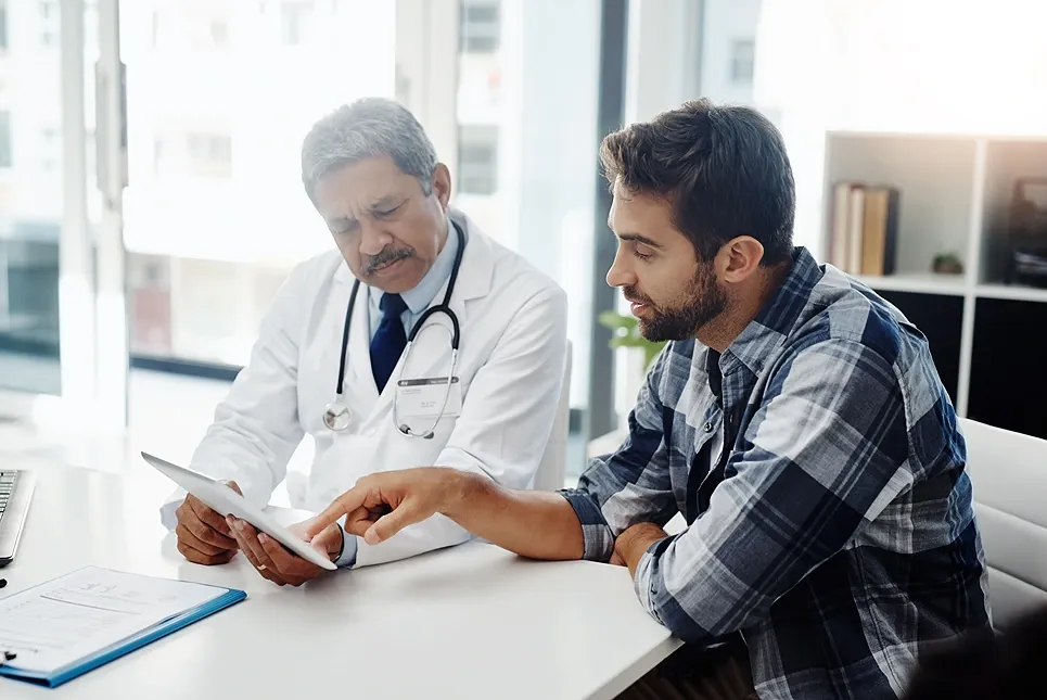 Doctor reviewing results on a tablet with a male patient