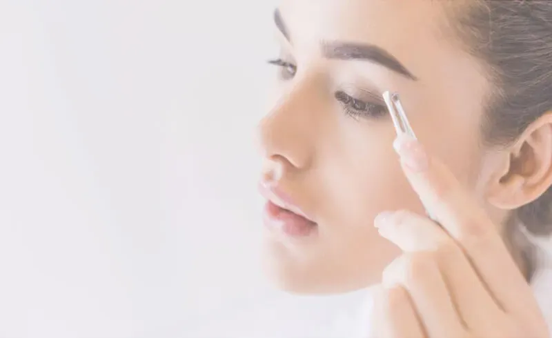 young woman plucking her eyebrows